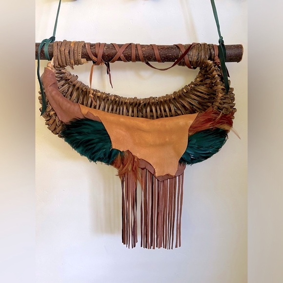 Handmade leather and wood basket weave with fringe and feathers.